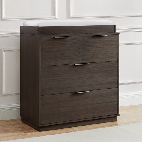 Wooden dresser with three drawers in a room with light-colored walls and wooden floor.