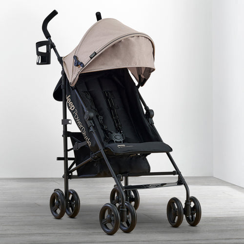 Beige and black stroller on a wooden floor with a white background
