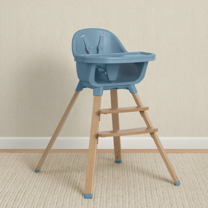 Blue high chair with wooden legs on a beige floor and wall. 2-babyGap Otto 3-in-1 High Chair