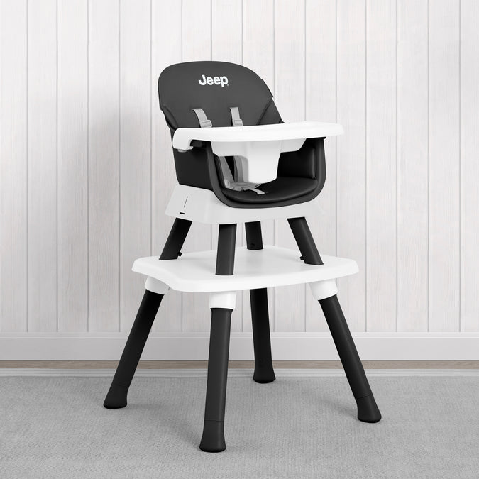 A black and white Jeep high chair with a white tray and seat, set against a white paneled wall and gray carpet. 33-Milestone 6-in-1 High Chair