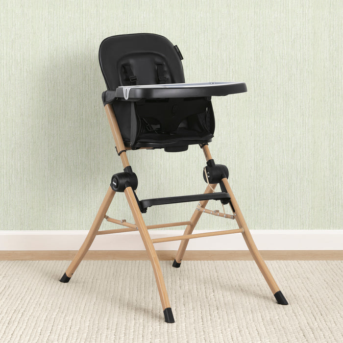 Black and beige high chair against a light-colored wall. 0-Dune Compact Travel High Chair