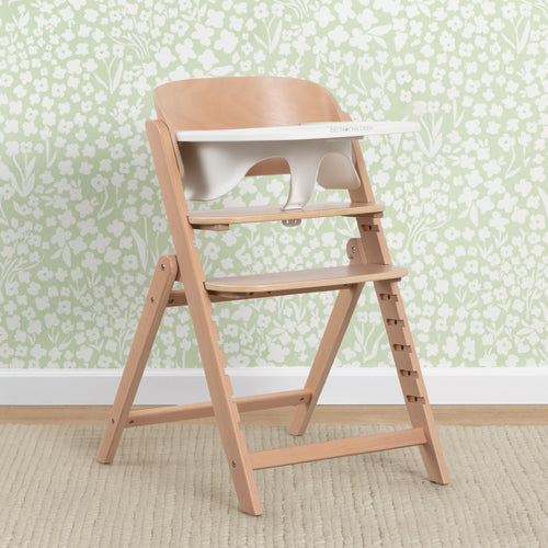 Wooden high chair against a floral wallpaper background