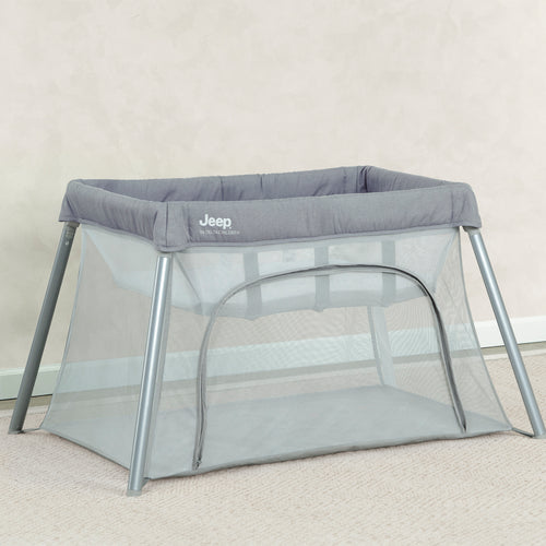 Gray portable crib with Jeep logo on a beige carpet