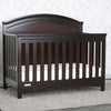 Dark wood crib in a room with a patterned wall. 24-Emma Crib 'N' More