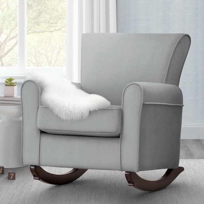 Gray rocking chair with a white pillow in a room with large windows. 19-Lancaster Rocking Chair featuring LiveSmart Fabric by Culp