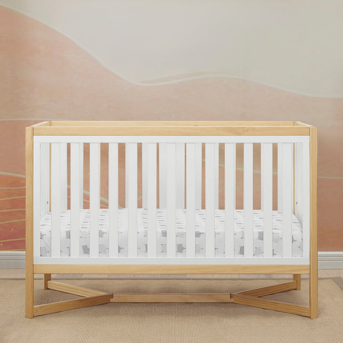 Wooden crib with white mattress in a room with pink walls. 0-Tribeca 4-in-1 Convertible Crib
