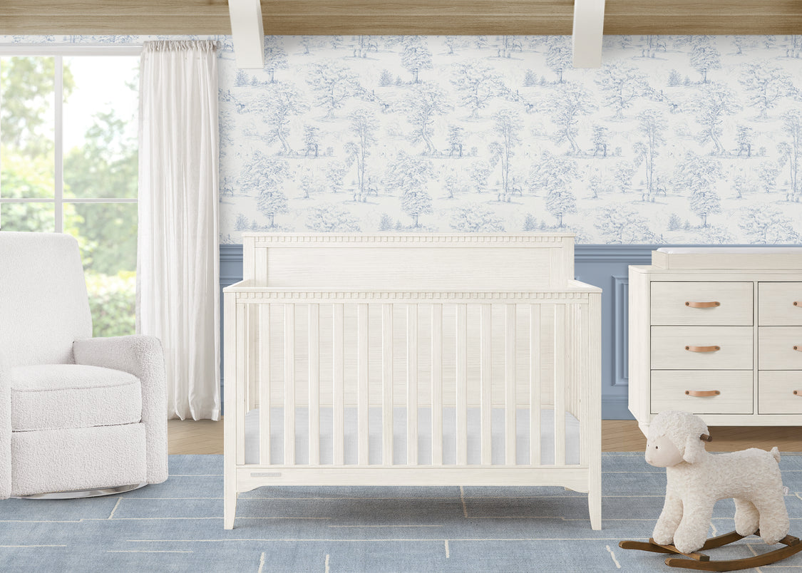 Nursery room with white crib, dresser, and chair against a floral wallpaper wall.