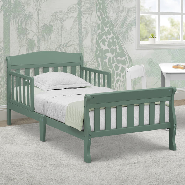 Green children's bed with white bedding in a room with patterned wallpaper and a window. 1-Canton Toddler Bed