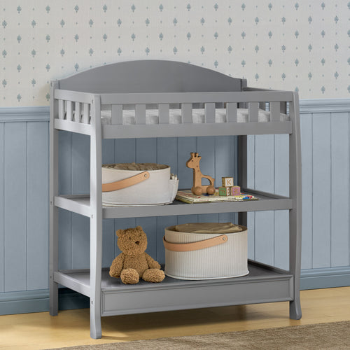 Gray changing table with toys and a basket in a child's room.