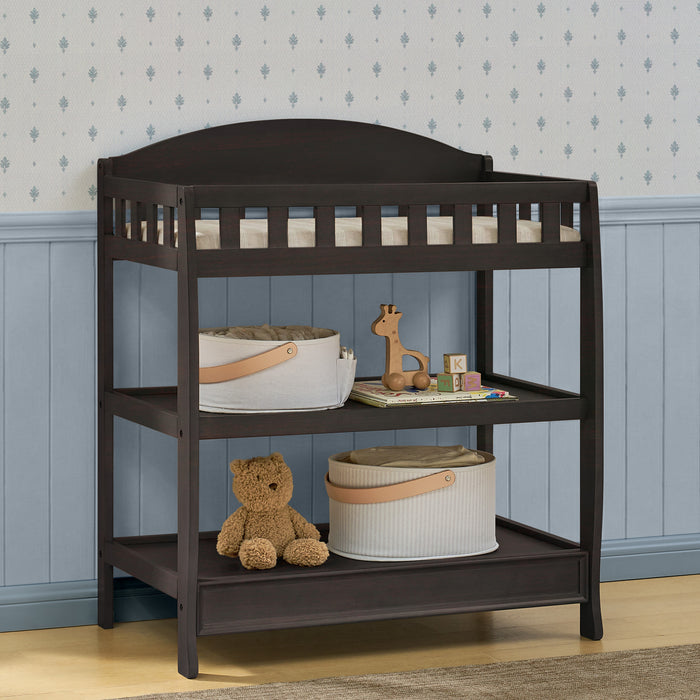 Dark wood changing table with toys and items against a patterned wall. 0-Wilmington Changing Table