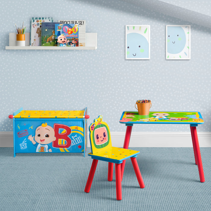 Children's table and chair set with colorful design in a room with blue walls and a shelf. 1-CoComelon 3-Piece Toddler Playroom Set