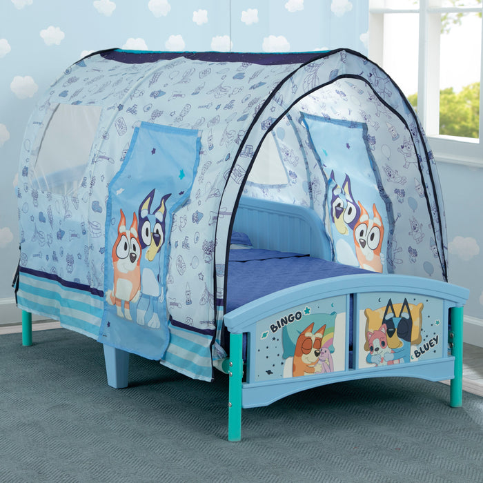 Children's bed with a blue and white canopy featuring cartoon characters in a room with light blue walls. 1-Bluey Plastic Toddler Bed with Tent