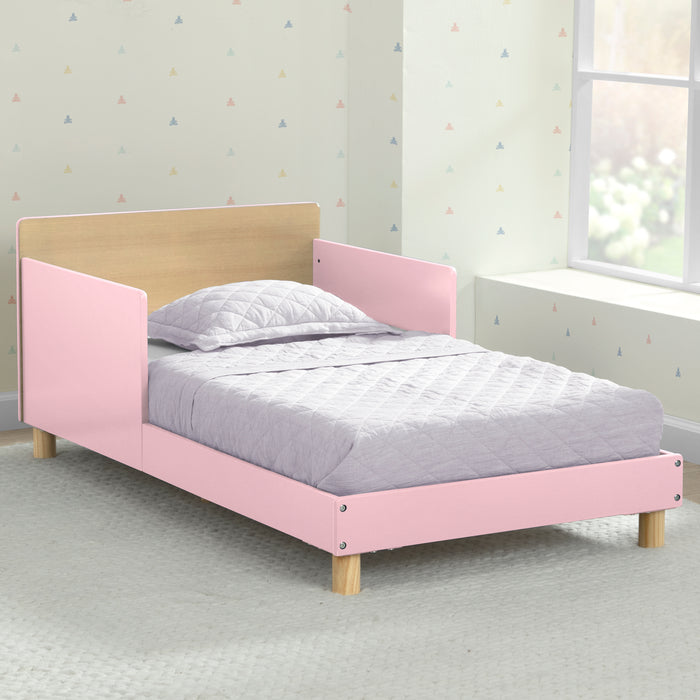 Pink and wooden bed in a room with light-colored walls and a window. 1-GapKids Wood Toddler Bed with Reversible Headboard