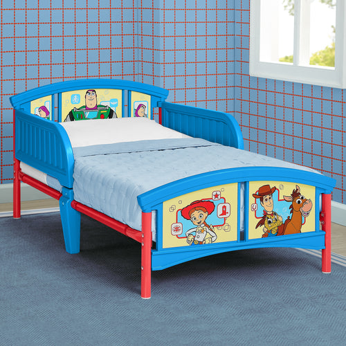 A children's bed frame in bright blue and red, featuring Woody and Buzz Lightyear character graphics on the headboard and footboard, shown in a room with blue grid-patterned wallpaper.