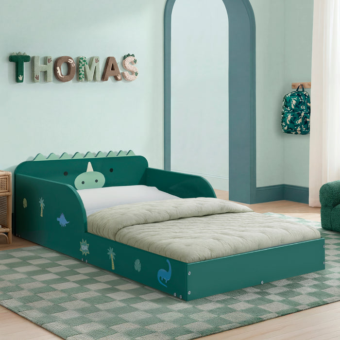 Children's bedroom with a green dinosaur-themed bed, decorative letters on the wall, and a backpack. 2-Dino Wood Floor Toddler Bed with Reusable Stickers
