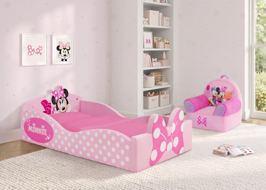 A pink Minnie Mouse children's bed with white polka dots and a matching pink chair in a bright, light pink nursery room.