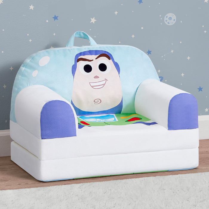 A children's plush armchair styled like Buzz Lightyear, featuring a large Buzz face on the backrest, white body, and blue accents, set against a starry blue wall. 0-Toy Story Buzz Lightyear Cozee Buddy Flip-Out Chair
