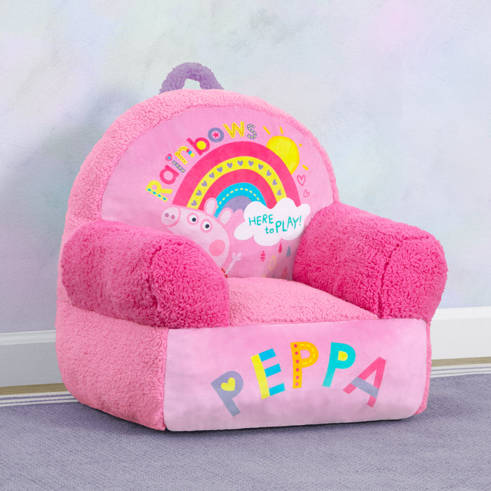 A pink Peppa Pig themed Cozee Buddy Chair with colorful graphics and a handle, placed in a room. 0-Peppa Pig Cozee Buddy Chair