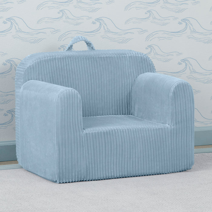 A blue corduroy chair with a carry handle, placed in a room with a matching blue wallpaper. 2-Cozee Corduroy Chair