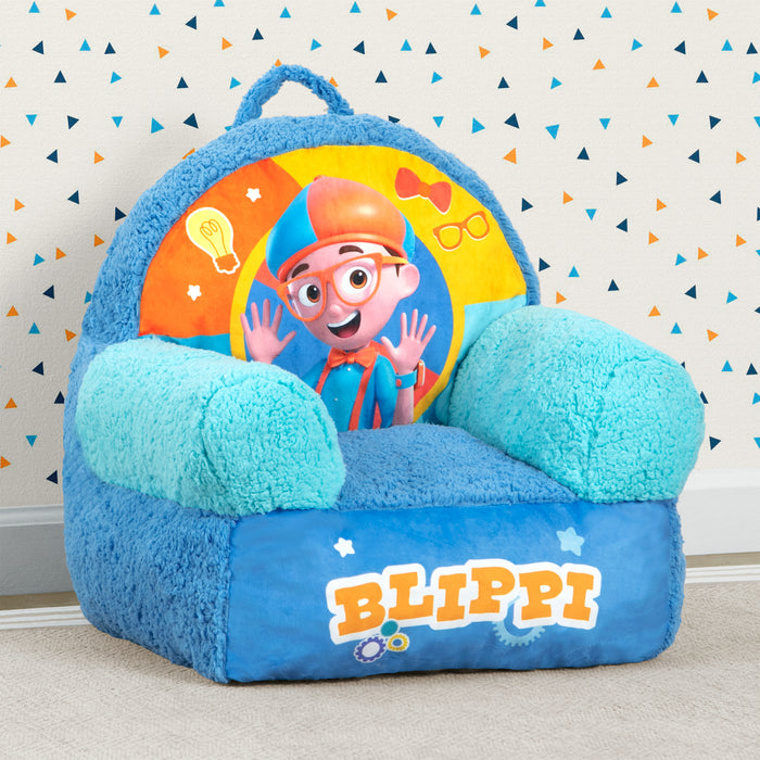 A blue plush chair with a colorful Blippi character design, featuring a handle and super-soft sherpa detailing. 0-Blippi Cozee Buddy Chair