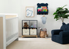Nursery room with white crib, blue chair, and decorative items on a white wall. 13-Brannan Bear Bookcase with Bins