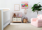 Nursery room with white crib, storage unit, and pink chair. 38-Brannan Bear Bookcase with Bins
