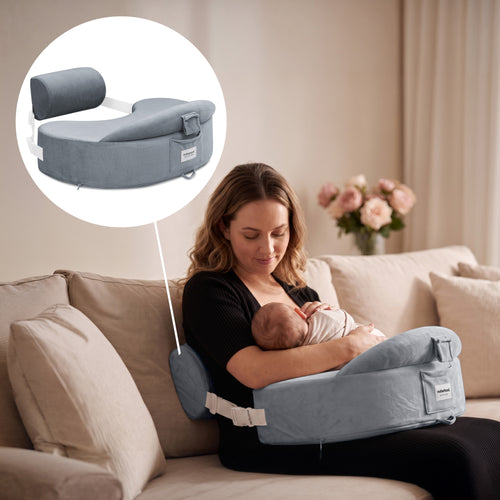 A woman in a black top sits on a beige couch holding a baby in a light blue nursing/support seat. A circular inset at the top left shows the light blue support seat by itself on a white background, with a line connecting the inset to the in-use scene.
