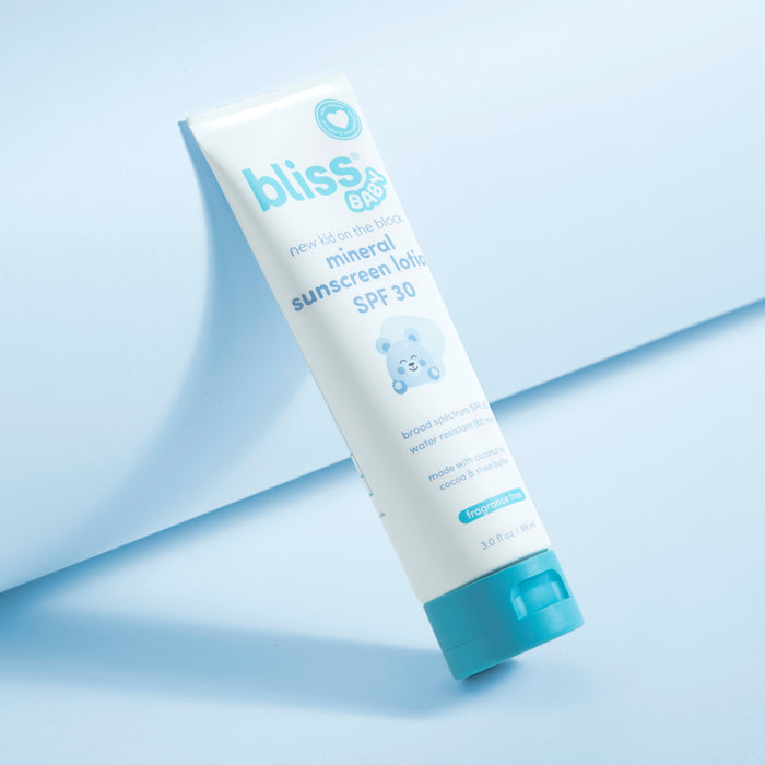 A tube of Bliss Baby mineral sunscreen SPF 30, featuring a white body with light blue text and a bright teal cap, set against a clean light blue background with a diagonal shadow. 1-New Kid on the Block Mineral Sunscreen Lotion - SPF 30