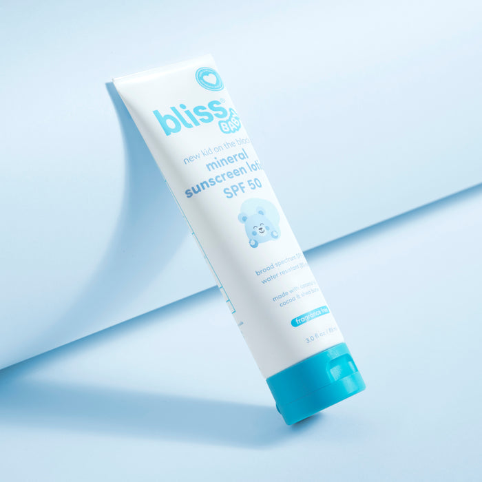 A tube of Bliss Bio mineral sunscreen lotion SPF 50, featuring a white body with light blue text and a bright blue cap, set against a clean light blue background with a soft shadow. 2-New Kid on the Block Mineral Sunscreen Lotion - SPF 50