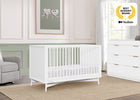 Nursery room with white crib, dresser, and gray chair, featuring a 'Best Nursery Brand' award on the wall. 22-Dylan 4-in-1 Convertible Crib