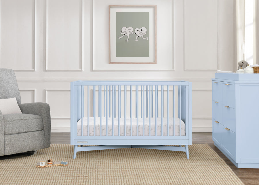 Nursery with light blue crib and dresser against a white paneled wall. 35-Dylan 4-in-1 Convertible Crib