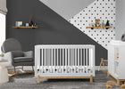 Nursery room with a white crib, gray armchair, and geometric wall design. 21-Poppy 4-in-1 Convertible Crib