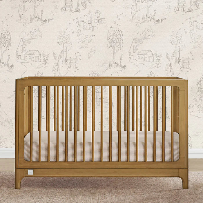 Wooden crib with white bedding against a wallpapered wall 1-babyGap Wren Collection