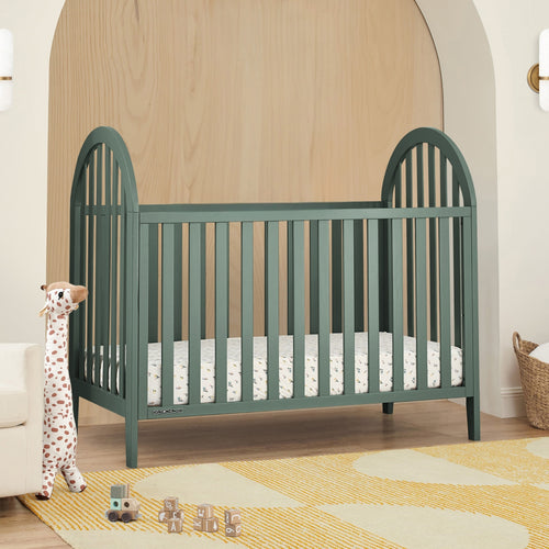 Green crib in a nursery with toys and a rug