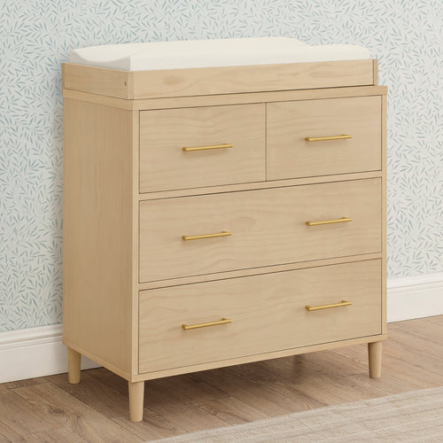 Beige dresser with gold handles against a patterned wall.