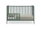 A sage green convertible crib with vertical slats, shown with a mattress and light-colored bedding on a solid white background. 23-Emmie 4-in-1 Convertible Crib