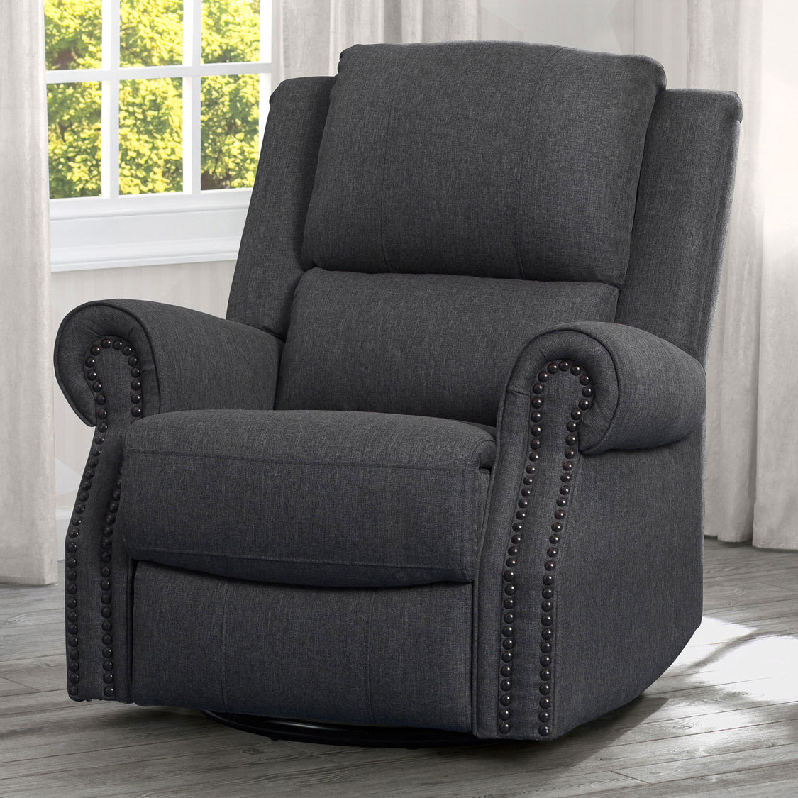 A beige upholstered recliner glider swivel chair with cushioned arms and nailhead trim, positioned in a nursery room.