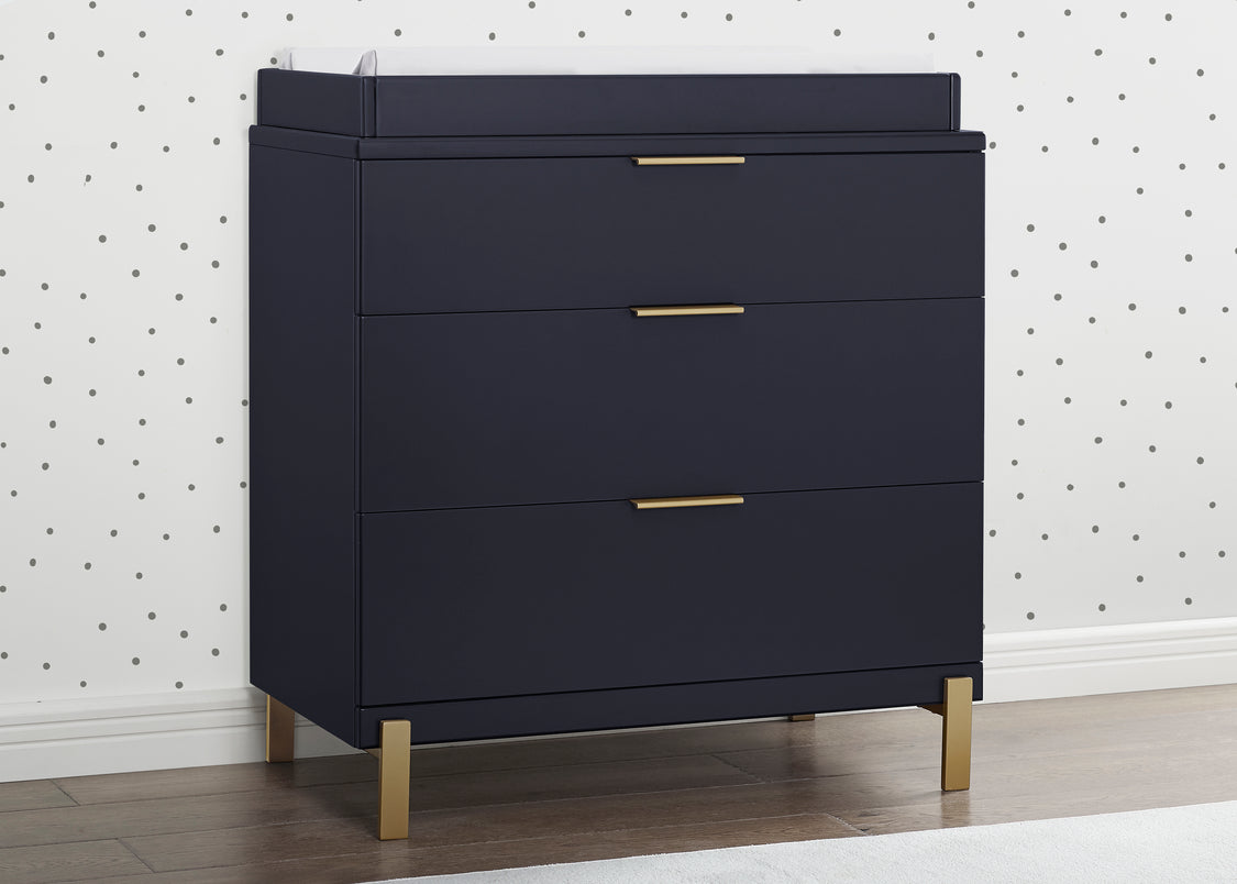 Navy blue dresser with gold legs and handles against a white wall with black dot pattern