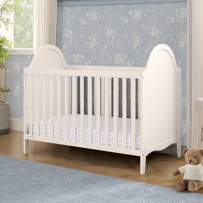 White crib in a nursery with floral wallpaper and a teddy bear. 29-Willa 4-in-1 Convertible Crib