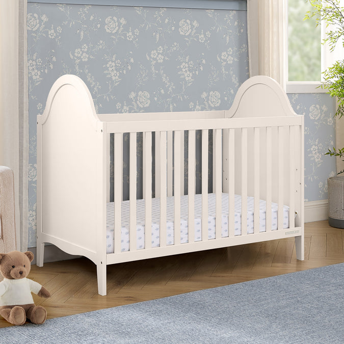 White crib in a nursery with floral wallpaper and a teddy bear. 31-Willa 4-in-1 Convertible Crib