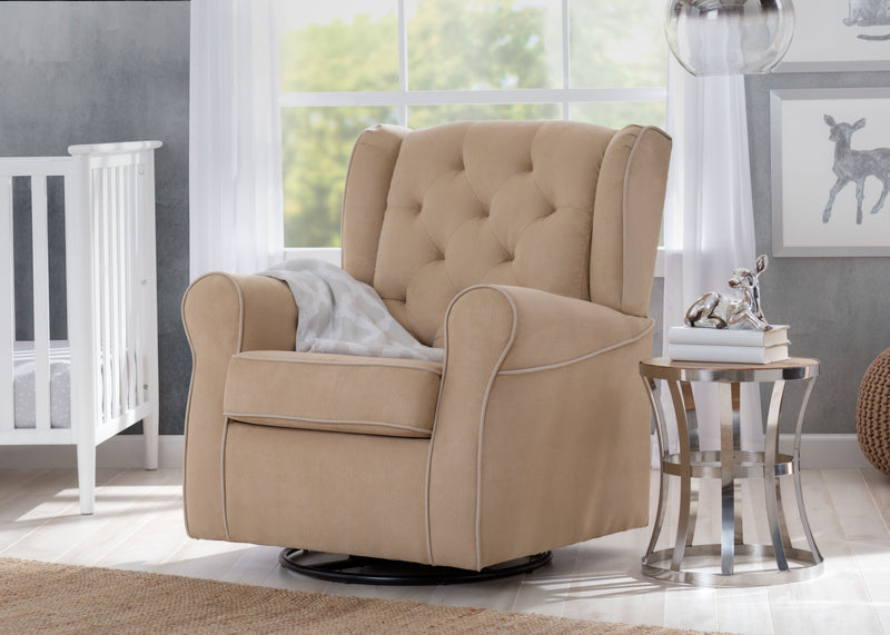 A beige upholstered recliner chair with tufted backrest and rolled arms, shown in a styled nursery setting next to a glass side table and crib.