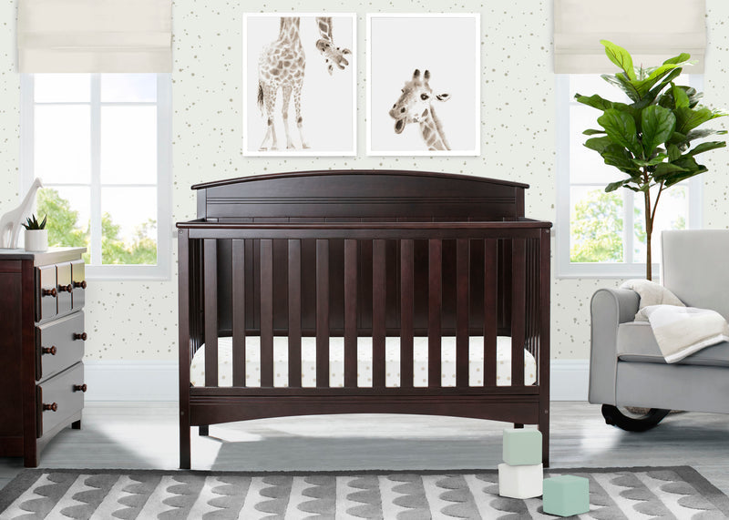 A dark brown wooden convertible crib in a styled nursery room, featuring giraffe wall art, a dresser, a gray armchair, and a patterned rug. 19-Archer 4-in-1 Convertible Crib