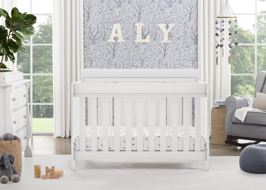 White crib in a bright nursery with decorative elements and a large window. 25-Richmond 6-in-1 Convertible Baby Crib