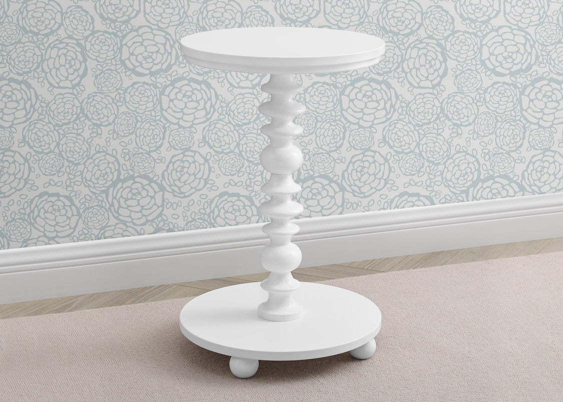 White side table with decorative design on a light-colored floor and patterned wall.