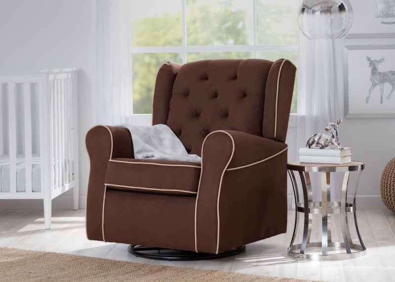 A brown tufted fabric swivel glider chair with cream piping, styled in a bright nursery next to a white crib and a small side table.