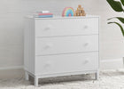 White dresser with three drawers against a light wooden paneled wall. 31-babyGap Legacy 3 Drawer Dresser with Interlocking Drawers