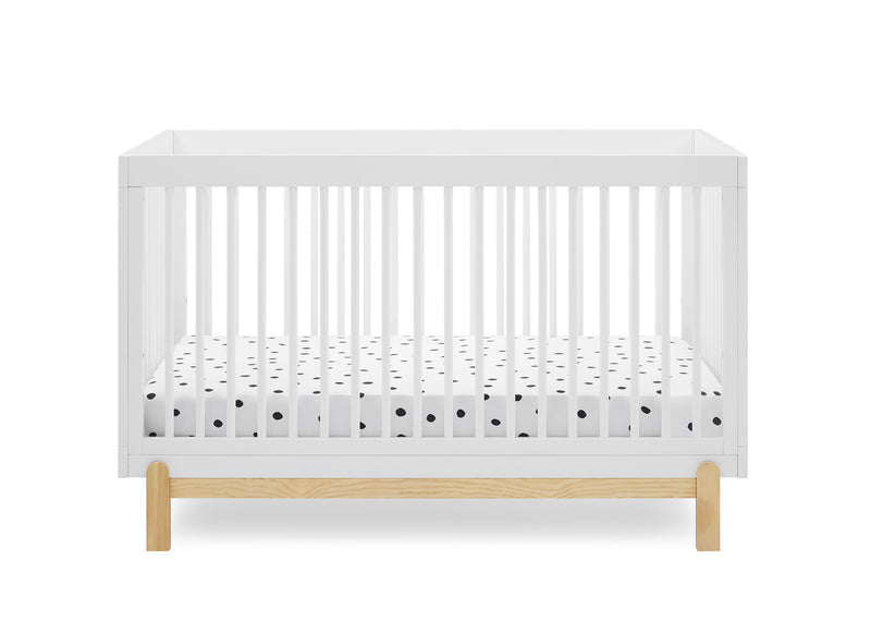 A white wooden baby crib with a natural oak base and a white mattress fitted with a black polka-dot pattern, shown against a solid white background. 22-Poppy 4-in-1 Convertible Crib