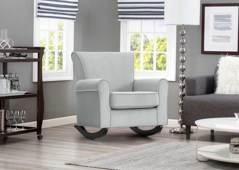Gray rocking chair in a living room with gray walls and a window.