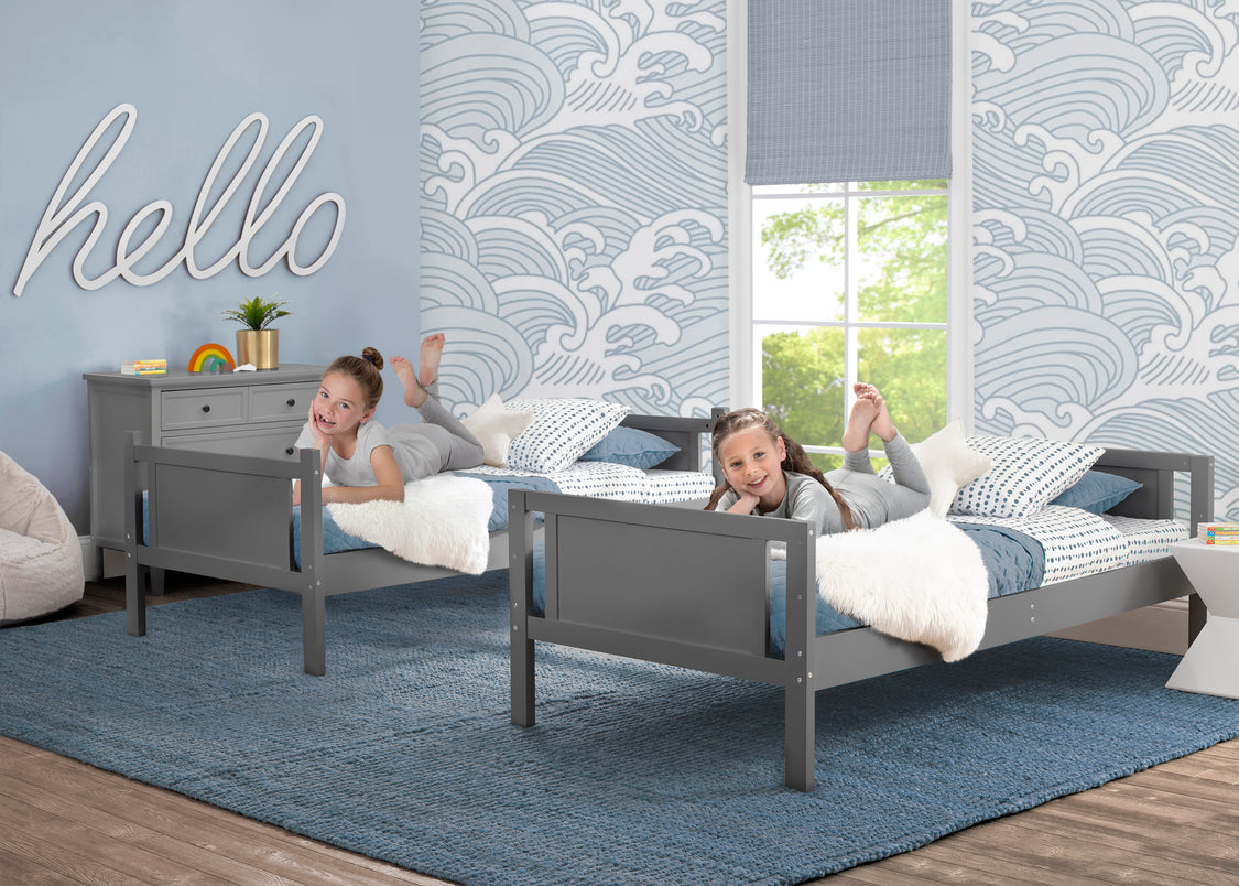 Two children playing on gray beds in a room with blue walls and decorative elements.