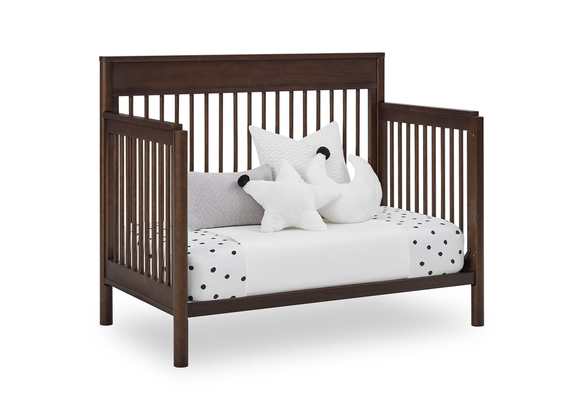 Wooden crib with white bedding and decorative pillows on a white background
